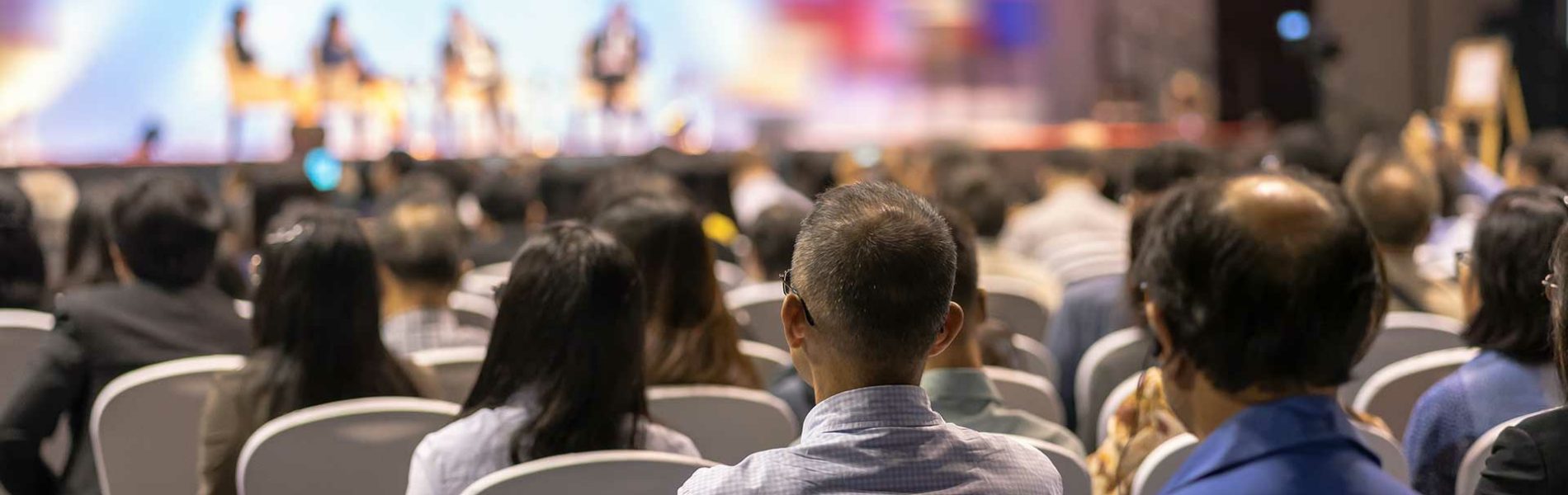 A crowd of attendees seated in chairs, engaged in a conference setting